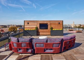 A wooden deck with red chairs and a television on a wooden box.